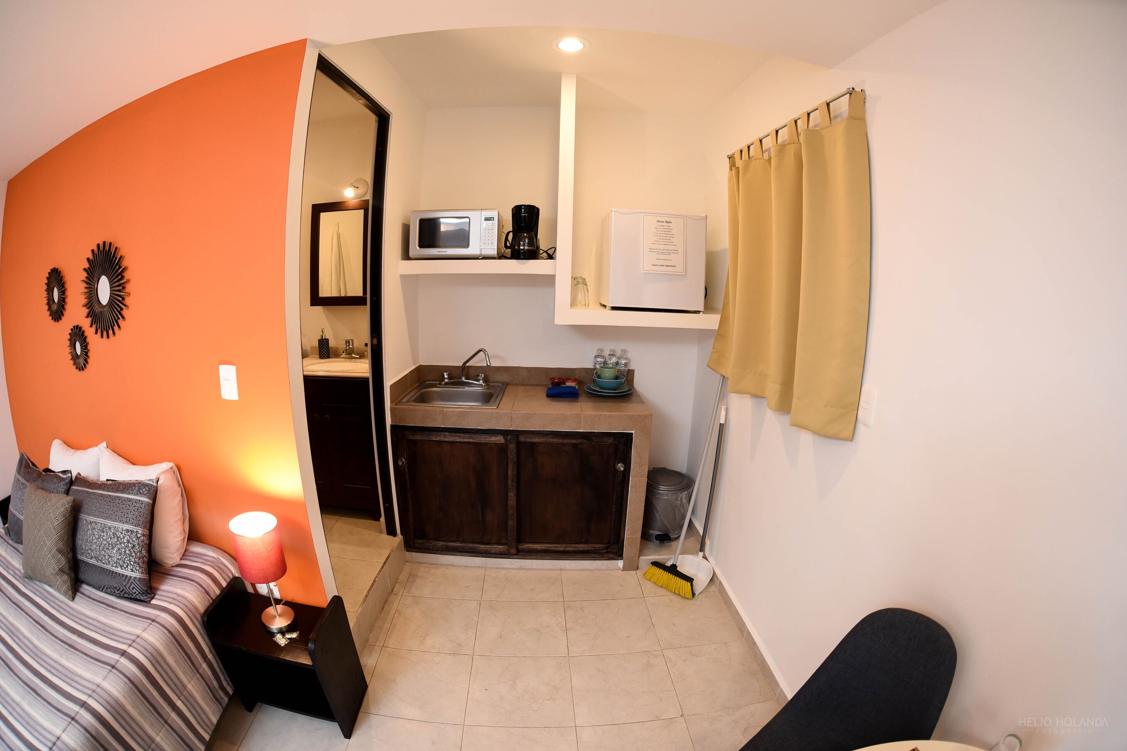 Una camera compatta con un letto, una scrivania, angolo cottura e bagno.
