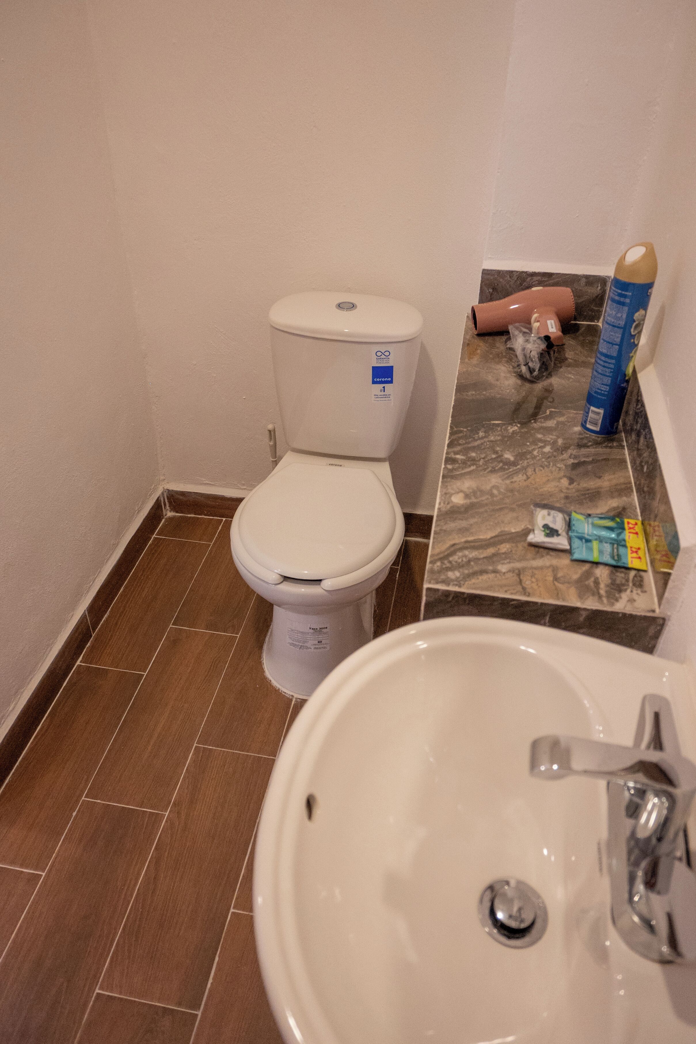 A bathroom with a toilet, sink, and marble-tiled floor.