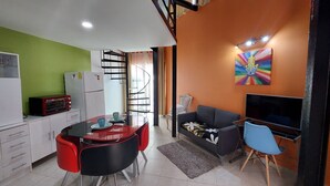 A compact living space with a kitchenette, a dining area with a glass table, a sofa, and a TV. - CANCUN SUITES APARTMENTS - HOTEL ZONE (Cancun)