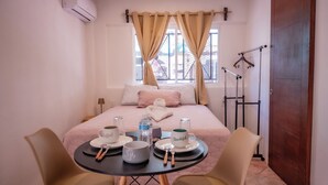 A neatly arranged hotel room with a bed, a small table with breakfast items, and a window with curtains. - CANCUN SUITES APARTMENTS - HOTEL ZONE (Cancun)