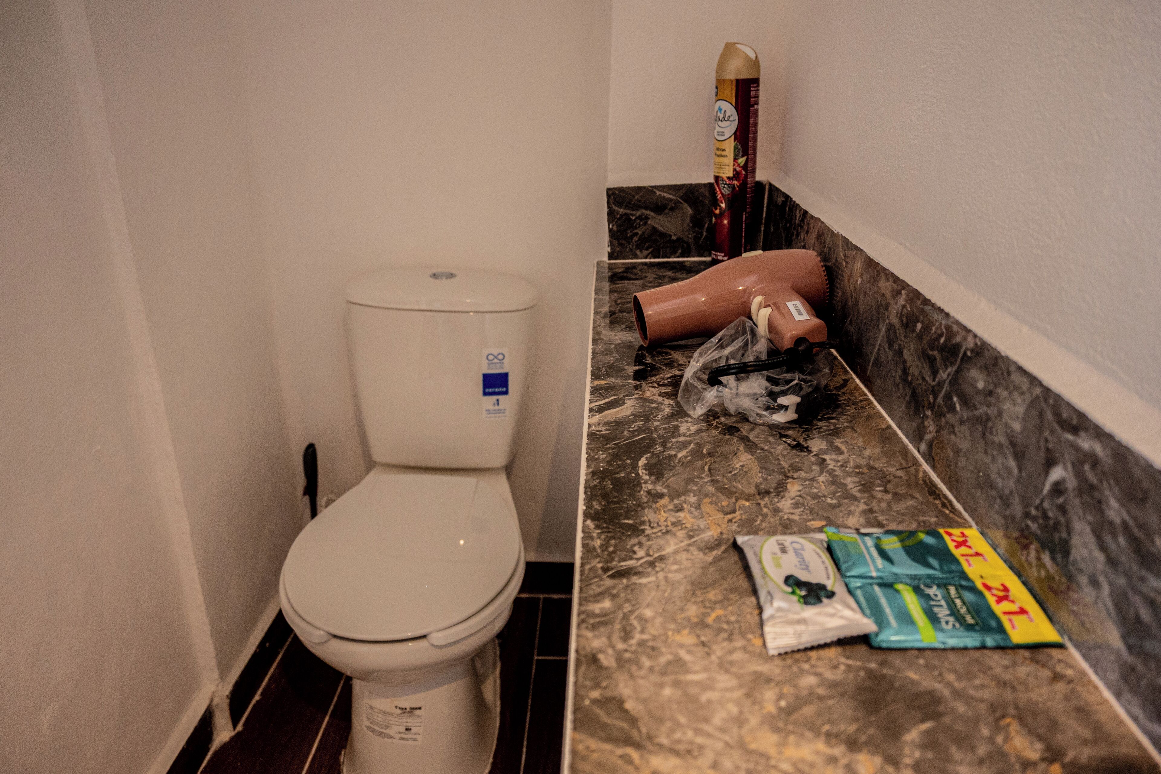 Ein Badezimmer mit Toilette, Mülleimer und Müllbeutel auf dem Boden.