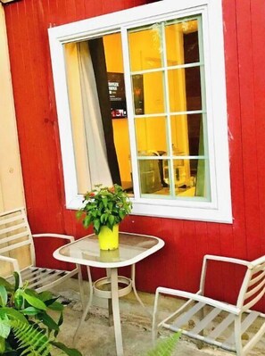 Sit and enjoy the view from this charming outdoor seating area with a potted plant and two comfortable chairs.
