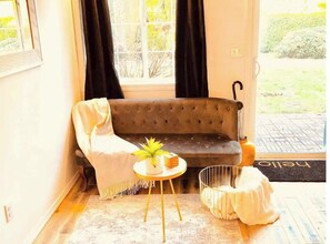 Relax in this inviting space with a sofa, table, and stool, surrounded by a potted plant and decorative accents.