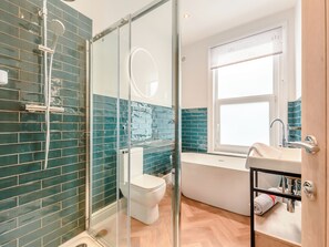 Une salle de bain moderne avec une douche à parois de verre, des toilettes blanches, une baignoire et un lavabo équipé d’un porte-serviettes.