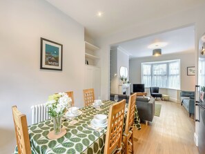 Un coin repas avec une table dressée pour quatre personnes, une cheminée, un téléviseur et un canapé en arrière-plan.