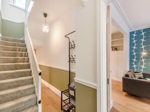 A staircase with a handrail, a coat rack with hanging items, and a wall with a geometric pattern.