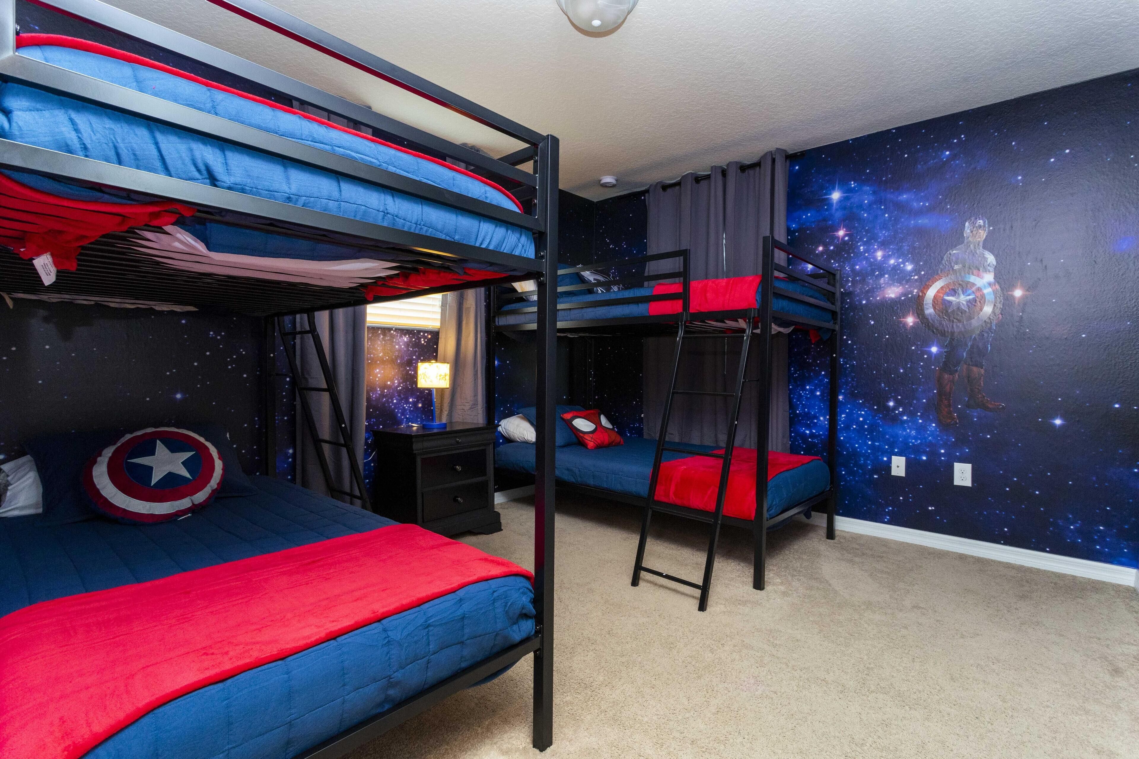 Habitación con literas, un mural de una galaxia estrellada, una almohada de Captain America y una manta roja.