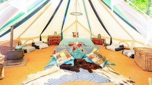 A cozy tent with a bed, a small table, and a portable stove. - 1 bedroom accommodation in Woolton Hill, nr Newbury (Woolton Hill, nr Newbury)
