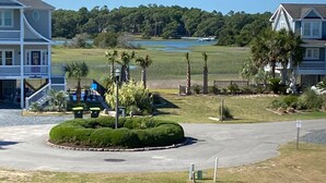 A residential area with a well-maintained lawn, a circular driveway, and a small park with palm trees.