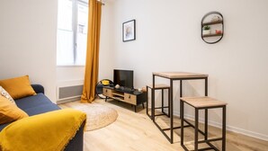 A modern living room with a sofa, a coffee table, a TV stand, and a small wooden table. - Opéra 9 - Great studio Opéra/Hôtel de Ville (Lyon)