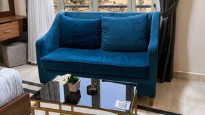 A room with a blue sofa, a glass coffee table, and a view of pyramids. - A pyramids view (Giza)