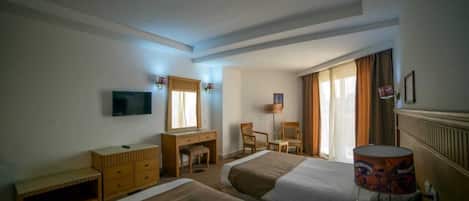Une chambre d’hôtel avec deux lits, un bureau, une chaise, une télévision et une lampe.