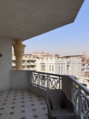 A balcony with a tiled floor, a chair, and a view of surrounding buildings. - A pyramids view (Giza)