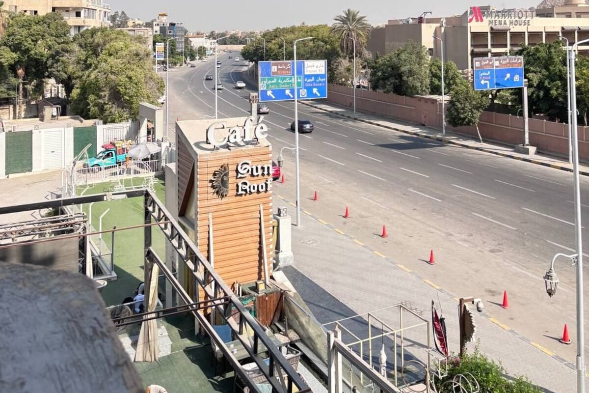 A road with multiple lanes, a hotel named "Marratoli Mena House" in the background, and a sign for "Cafe Sun Roots" in the foreground.