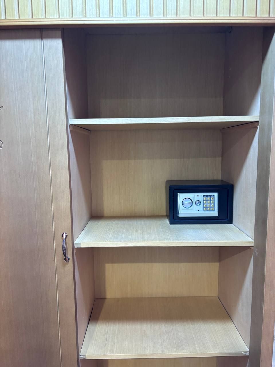 A wooden cabinet with three shelves, one of which contains a black safe.