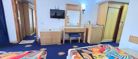 A hotel room with two beds, a desk, a dresser, a television, and a mirror.