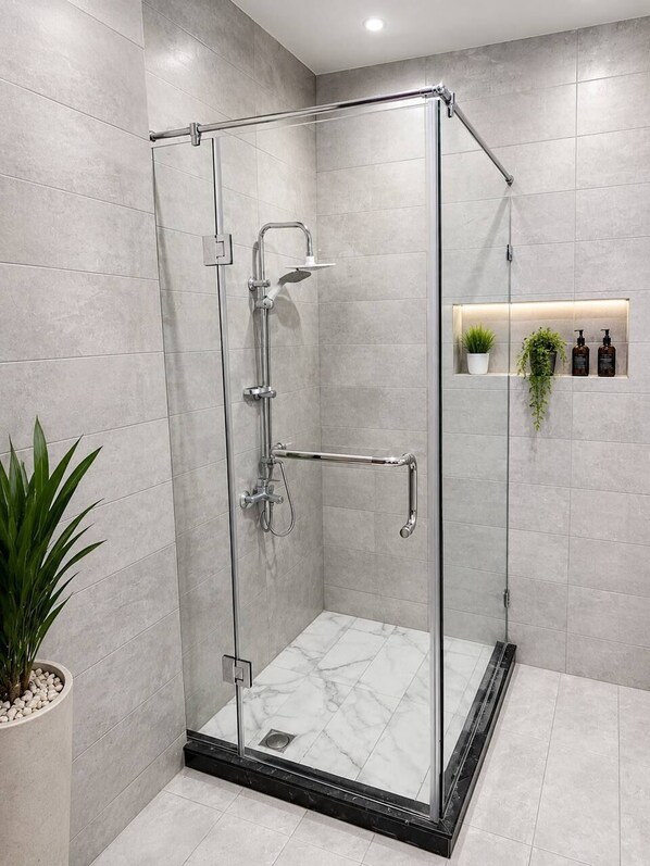 A glass-enclosed shower with a handheld showerhead, a handheld showerhead, and a wall-mounted faucet. - A pyramids view (Giza)