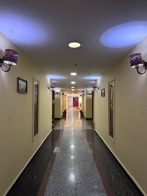 A hotel hallway with a polished floor, recessed lighting, and wall-mounted sconces. - A pyramids view (Giza)