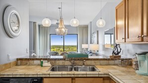 Une cuisine moderne dotée d’un lave-vaisselle encastré, d’un évier à deux bacs et d’une grande fenêtre offrant une vue panoramique.