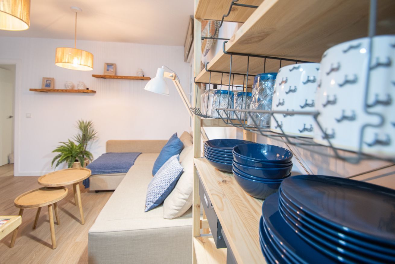 A modern living room with a sofa, a small table, and shelves with dishes.
