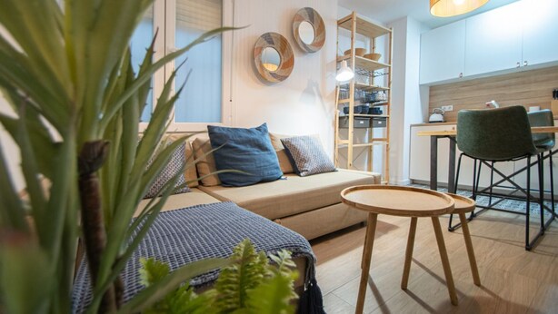 Un salon moderne avec un canapé, une petite table ronde et un coin repas équipé d’une chaise.