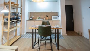 Une cuisine compacte équipée d’un four à micro-ondes, de placards en bois et d’une table à manger avec deux chaises.