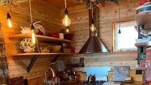 A rustic kitchen with wooden walls, a central island, a stove, and a microwave.