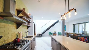 A modern kitchen with a gas stove, wooden shelves, and a large island.