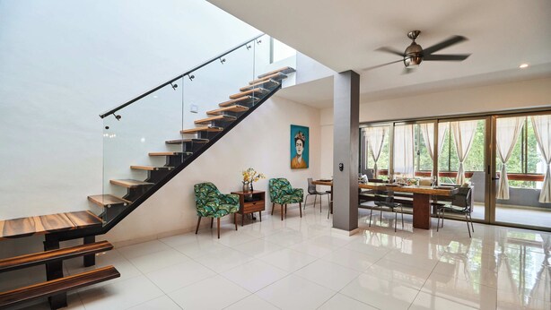 A modern interior with a staircase, seating area, and large windows.