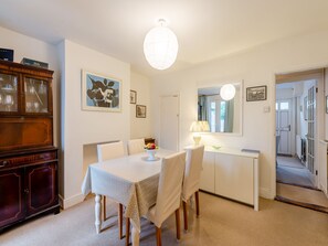 A dining area with a table, chairs, a cabinet, and a lamp.