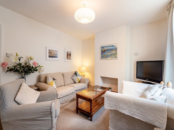 A living room with a sofa, armchairs, a coffee table, a TV, and artwork on the walls.