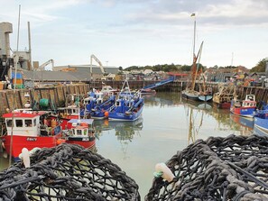 A harbor with multiple boats docked, a crane, and industrial buildings.