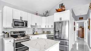 Una cocina moderna con armarios blancos, electrodomésticos de acero inoxidable y una isla de mármol.