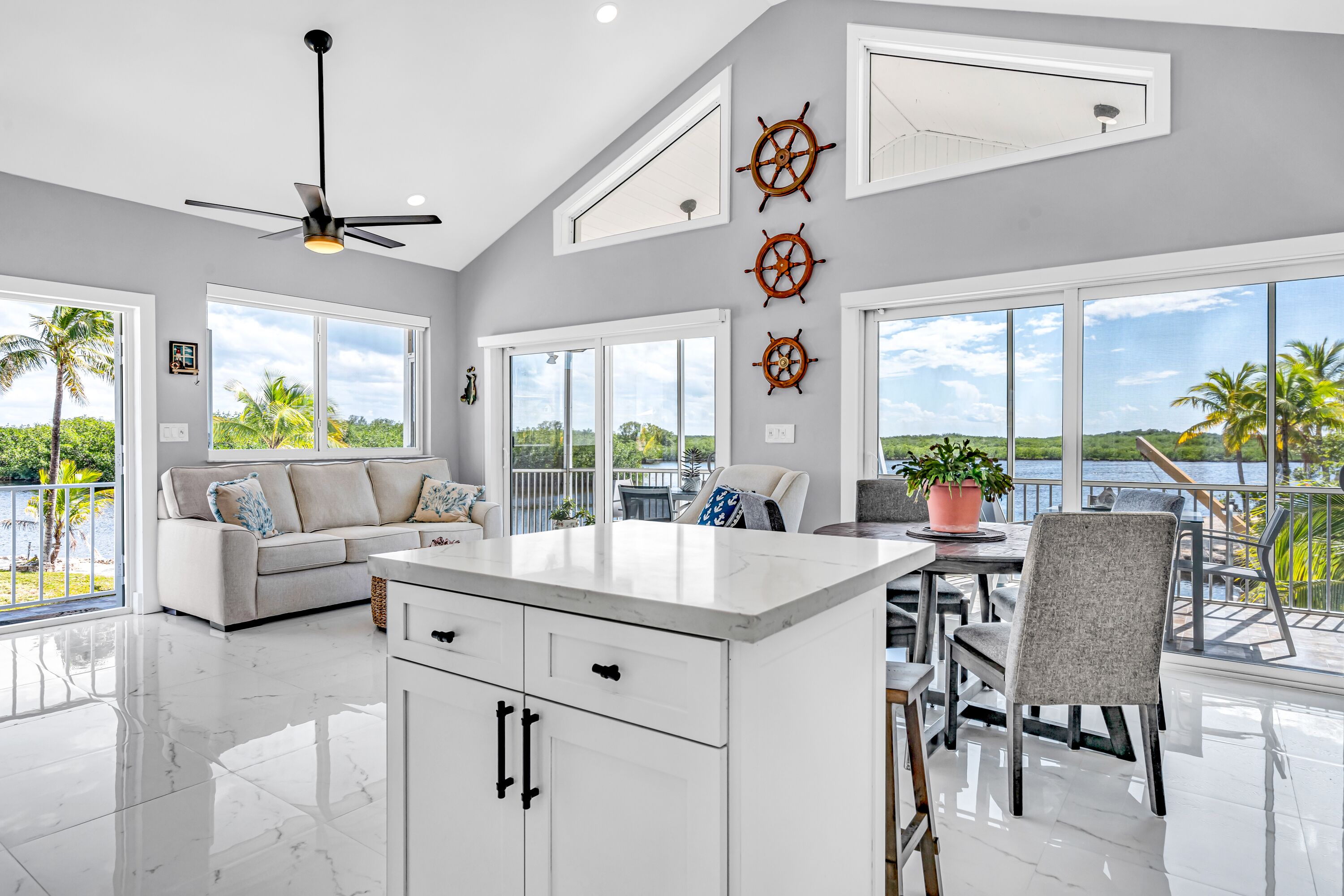 A modern kitchen with a large island, white cabinetry, and a view of a lake.