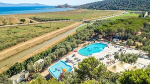 Un resort con dos piscinas, un río y vistas al mar y a las montañas.
