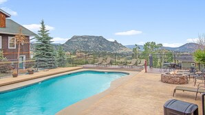 A swimming pool with a mountain view, outdoor seating, and a fire pit. - Notchtop Mountain Condo (Estes Park)