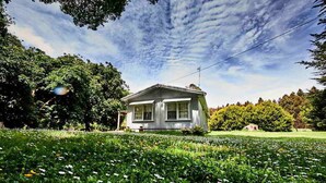 A house surrounded by a lush garden with a clear sky. - Tarkinegrove... welcome to the wild side. (Roger River)