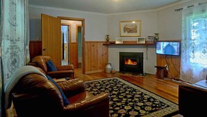 A living room with a fireplace, leather sofa, and a television. - Tarkinegrove... welcome to the wild side. (Roger River)