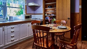 A kitchen with white cabinets, a wooden dining table with four chairs, a microwave, and a stove. - Tarkinegrove... welcome to the wild side. (Roger River)