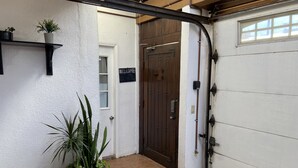 Een garage deur, een welkomstbord en een bloempot.