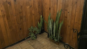 Een hoekzaal met houten wanden, een betegelde vloer en twee potplanten.
