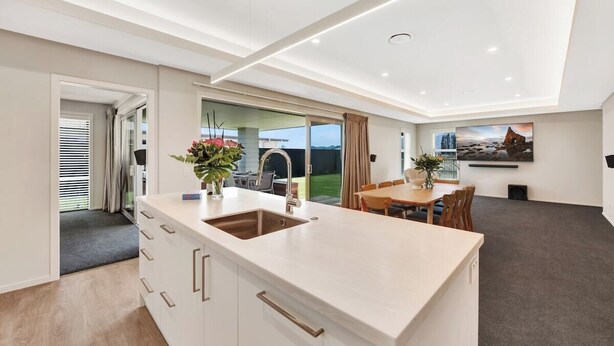 Une cuisine moderne dotée d’un îlot central, d’un coin repas avec une table et des chaises, et d’une grande fenêtre offrant une vue sur l’extérieur.