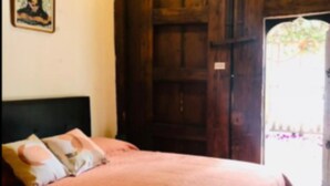 Ein Schlafzimmer mit Bett, Kissen, einer Holztür und einem gerahmten Bild an der Wand.