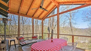Une terrasse extérieure couverte, équipée d’une table et de chaises, d’un canapé et d’un ventilateur de plafond.
