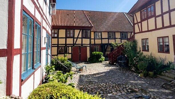 A courtyard with cobblestone paths, traditional half-timbered houses, and potted plants. - 2 bedroom awesome apartment in Ystad (Ystad)