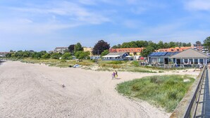 A beach with a wooden boardwalk, a covered seating area, and buildings in the background. - 2 bedroom awesome apartment in Ystad (Ystad)