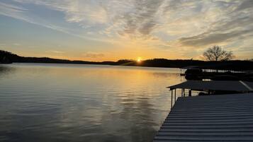 A calm lake at sunset with a dock extending into the water.