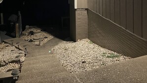 Ein Gebäude bei Nacht mit schrägem Dach und einer kleinen Veranda mit Kies.