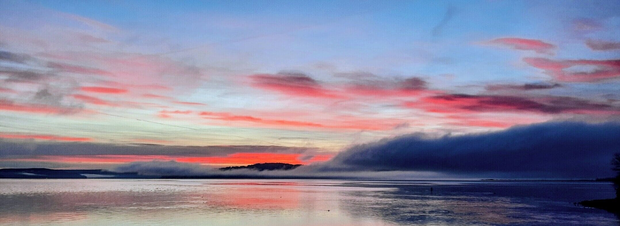 Une scène de plage avec une mer calme qui reflète le ciel.
