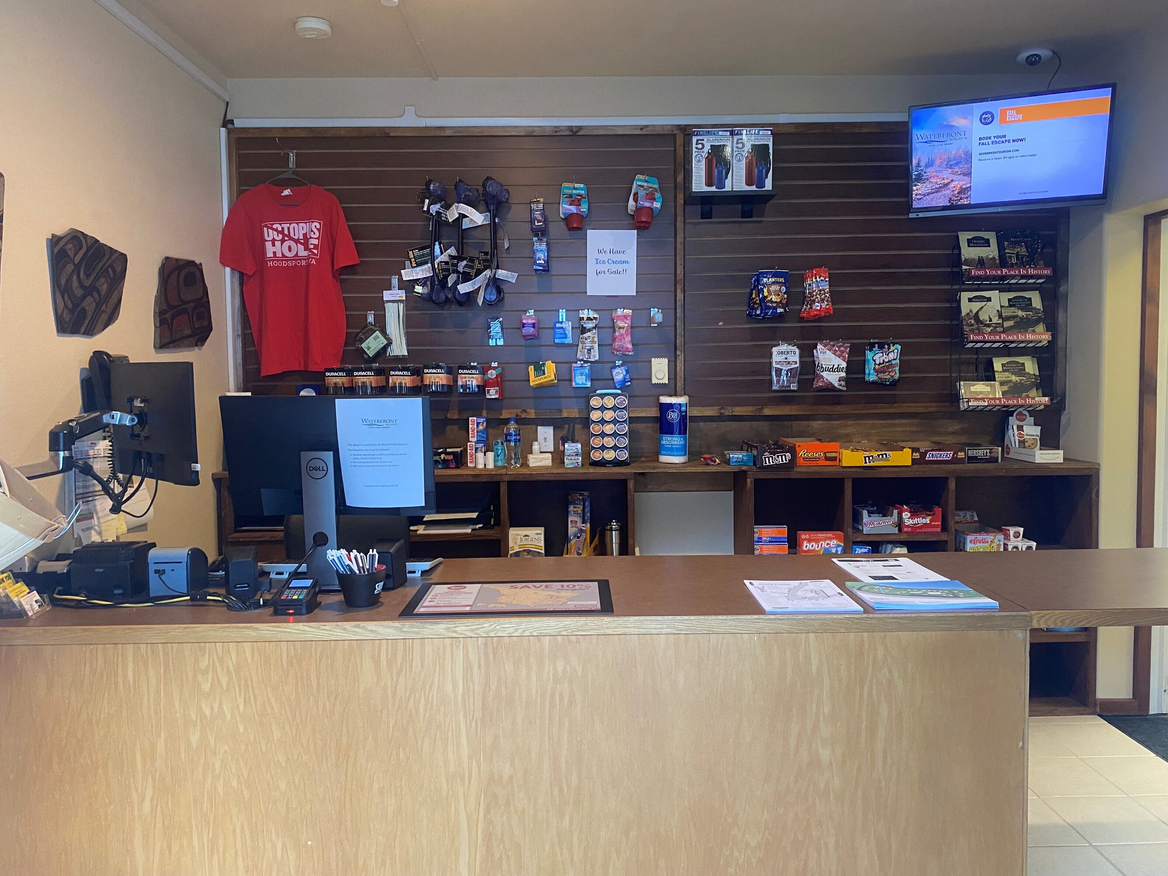 A retail store with a wooden counter, various products on shelves, and a computer monitor.
